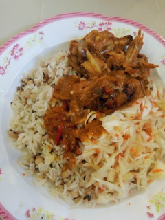 A picture of Rice and beans wit chicken souce and salad.