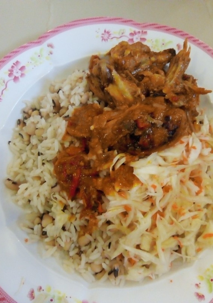 A picture of Rice and beans wit chicken souce and salad.