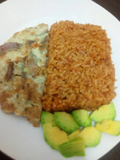 A picture of Jollof rice with fried egg and avacado.
