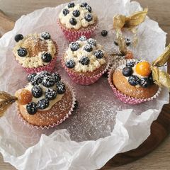 A picture of Blueberries and vanilla frosted cup cakes.