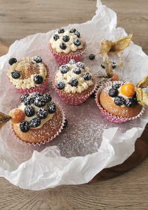 A picture of Blueberries and vanilla frosted cup cakes.