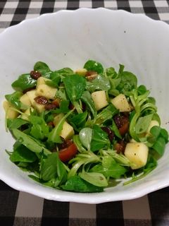 Una foto de Ensalada de rúcula, canónigos, tomate, manzana y uvas pasas