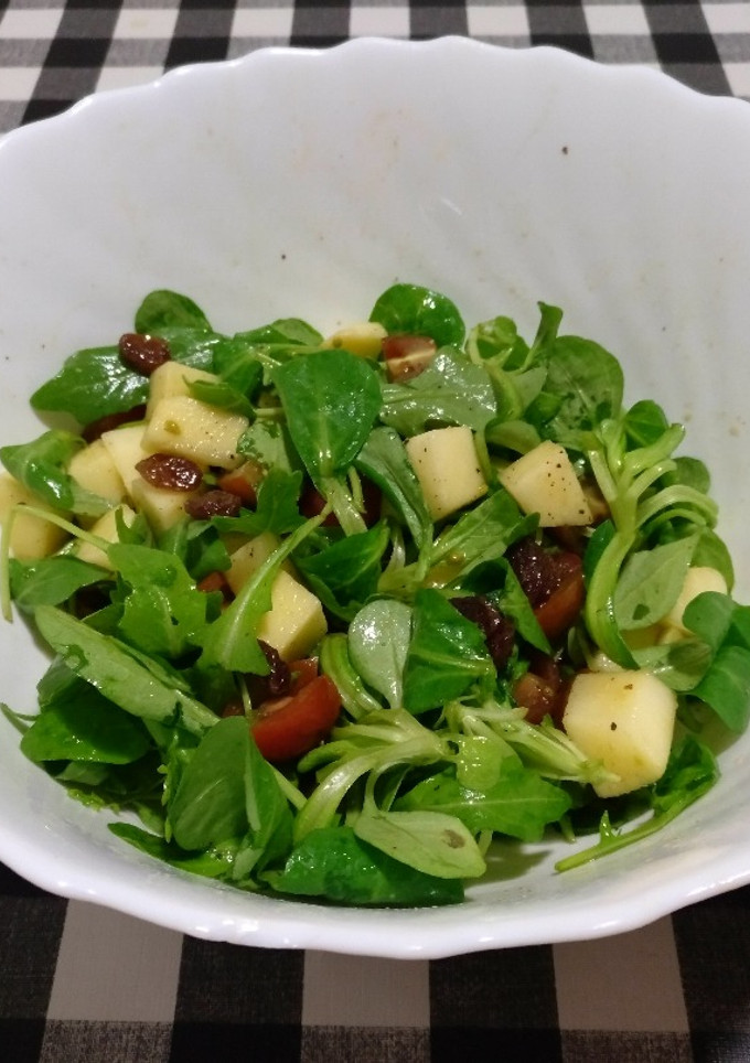 Una foto de Ensalada de rúcula, canónigos, tomate, manzana y uvas pasas