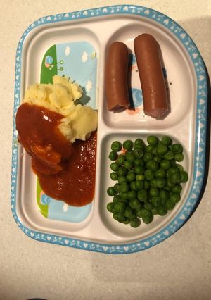 A picture of Mashed potatoes and peas with chicken sausage.