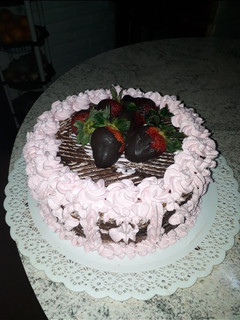 Una foto de Torta de chocolate decorada con crema chantilly y frutillas