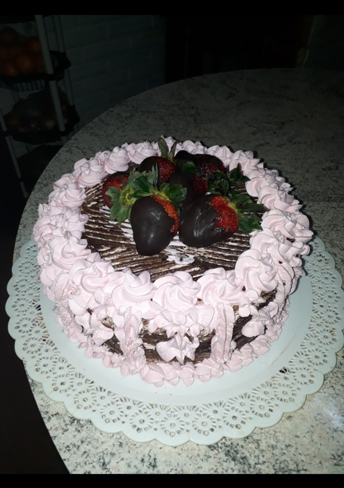 Una foto de Torta de chocolate decorada con crema chantilly y frutillas