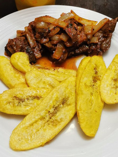 Una foto de Bistec Hígado en Achiote y Ají de Panca con Tajadas