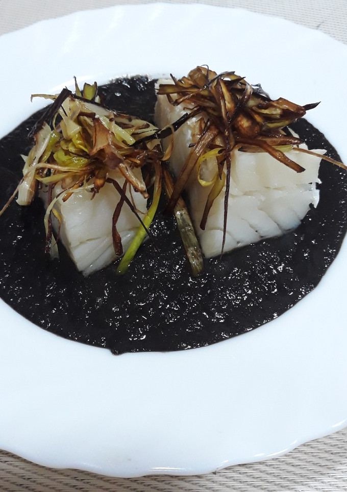 Una foto de Bacalao confitado a baja temperatura al horno con salsa de tinta
