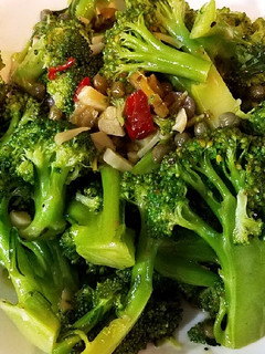 A picture of Steamed broccoli with chili and olive sauce.