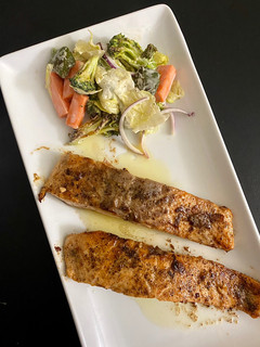 A picture of Salmon in lemon butter sauce with baked veggies.