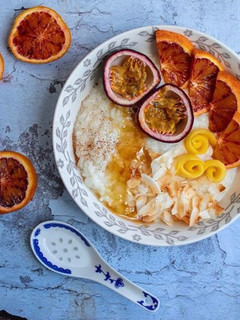 A picture of Rice porridge with almond milk, roasted coconut flakes, ground cinnamon, honey and mixed fruits.