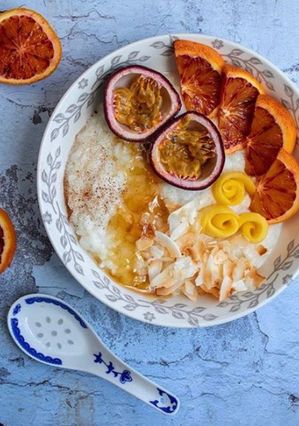A picture of Rice porridge with almond milk, roasted coconut flakes, ground cinnamon, honey and mixed fruits.