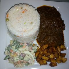 A picture of Green pepper sauce with white rice and plantain + salad.