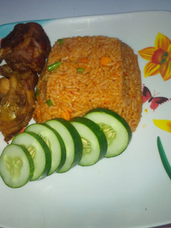 A picture of Jollof rice and Turkey with cucumber.