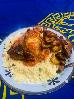 A picture of Garnished Rice and fried fish with plantain.