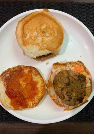 A picture of Bun sandwich with raw banana tikki and veggies.