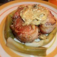 A picture of Solomillo de cerdo envuelto en panceta con crema de mostaza con guarnición de puerros.