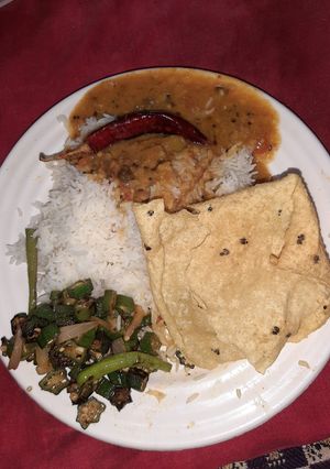 A picture of Dal fry fried bhindi papad and plain rice.