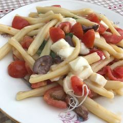 A picture of Pasta mozzarella, tomatoes and olives.