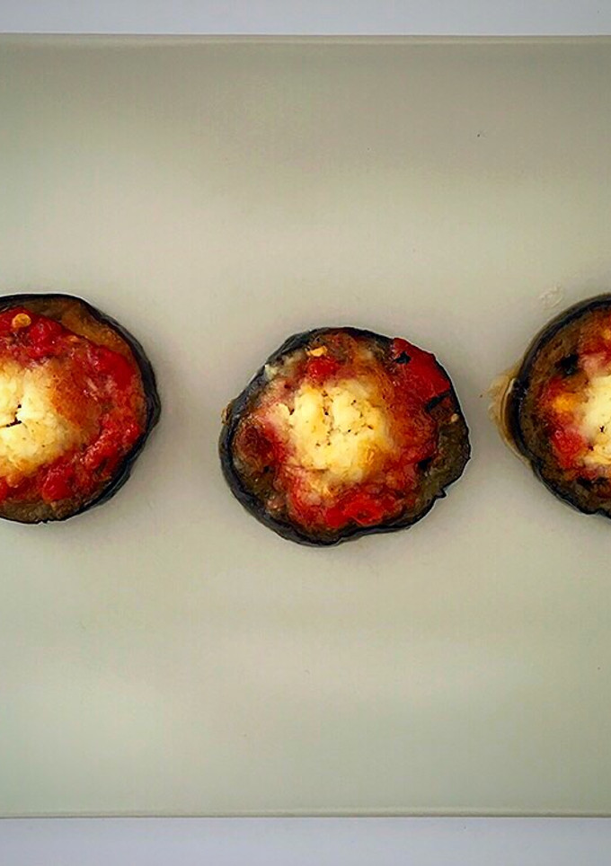 Una foto de Berenjena, tomate especiado y rulo de cabra