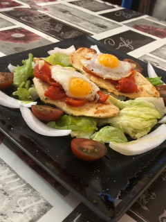 Una foto de Milanesa de pollo con cama de ensalada pimientos asados y huevos de codorniz