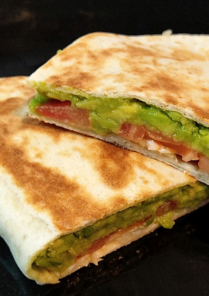 Una foto de Tortilla de trigo rellena de aguacate, tomate y queso