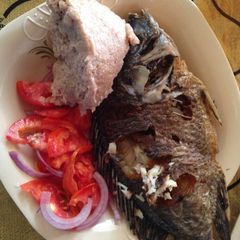 A picture of Ugali wa mtama served with fried fish and kachumbari.