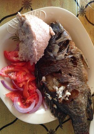 A picture of Ugali wa mtama served with fried fish and kachumbari.