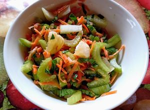 Una foto de Ensalada de apio con sus hojas, zanahoria y trocitos de limón