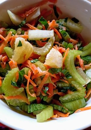 Una foto de Ensalada de apio con sus hojas, zanahoria y trocitos de limón