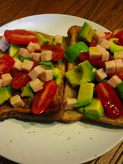 Una foto de Tostadas de pan con semillas de sésamo y lino, aguacate, tomates y pavo