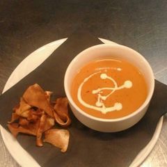 A picture of Cream of tomato soup with parsnip crisps.