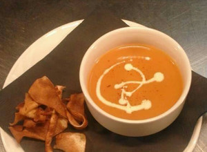 A picture of Cream of tomato soup with parsnip crisps.