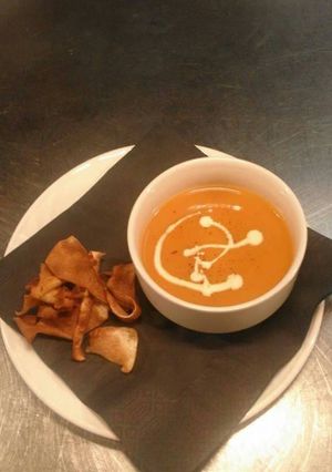 A picture of Cream of tomato soup with parsnip crisps.