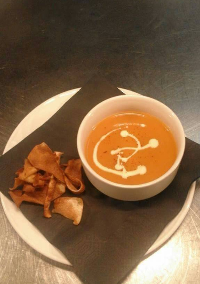 A picture of Cream of tomato soup with parsnip crisps.