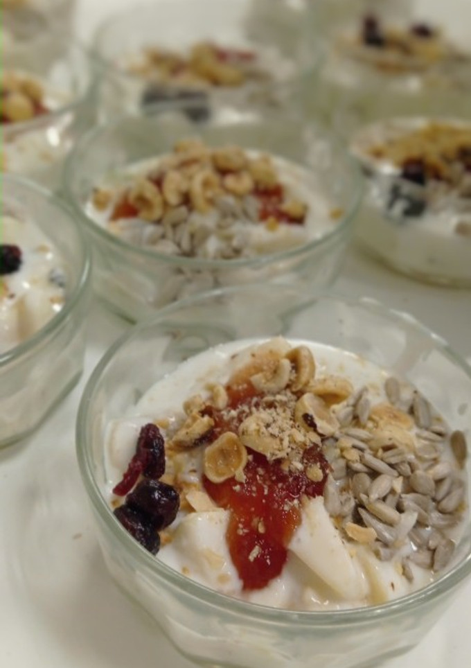 Una foto de Postre de yogurt con mermelada y frutas, adornado con avellanas