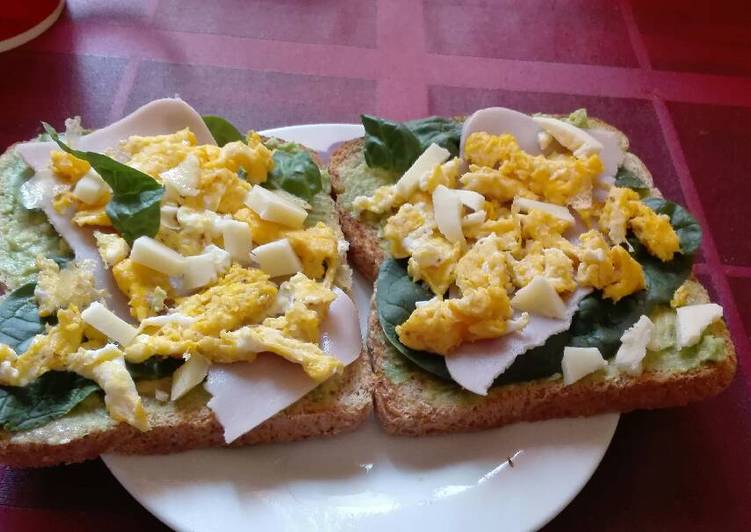 Tostadas untadas con aguacate, espinaca, pavo y huevo revuelto