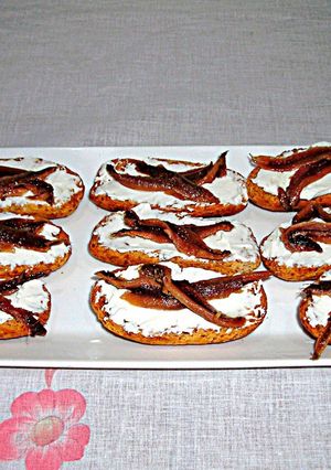 Foto principal de Tapitas de anchoas y queso crema sobre rebanas de pan tostado