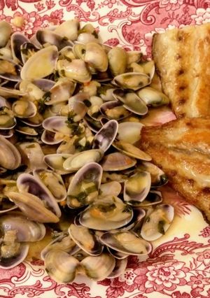 Una foto de Coquinas salteadas con txakolí y corvina a la plancha