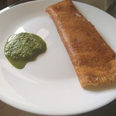 A picture of Masala dosa with potato and coconut chattny.