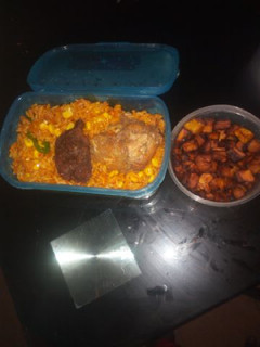 A picture of Jollof rice with fried plantain and chicken.