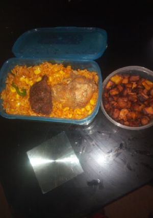 A picture of Jollof rice with fried plantain and chicken.