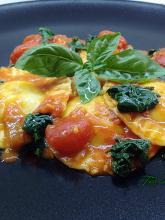 A picture of Ravioli with Burrata and Basil Pesto Filling, with Cherry Tomatoes and Greens.