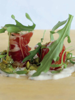 Una foto de Jamón serrano, crema de queso manchego, rúcula y pistacho