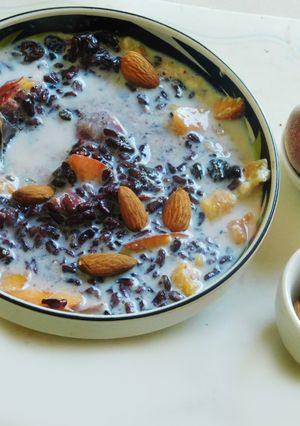 A picture of Black rice porridge with fruits and nuts.