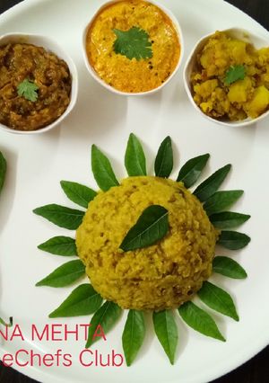 A picture of Khichdi with Dahi Tikhari, jeera aloo, baigan chutney.