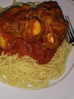 A picture of Spagetti with tomato sauce and boiled egg.