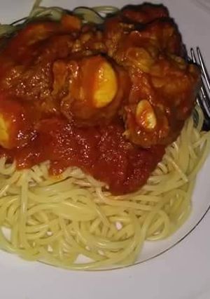 A picture of Spagetti with tomato sauce and boiled egg.