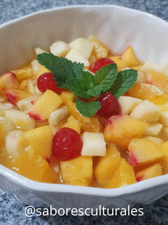 Una foto de 🍒 🍎🍌🍊Ensalada de frutas con hojas frescas de menta y melisa