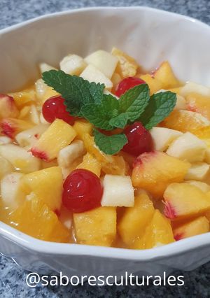 Una foto de 🍒 🍎🍌🍊Ensalada de frutas con hojas frescas de menta y melisa